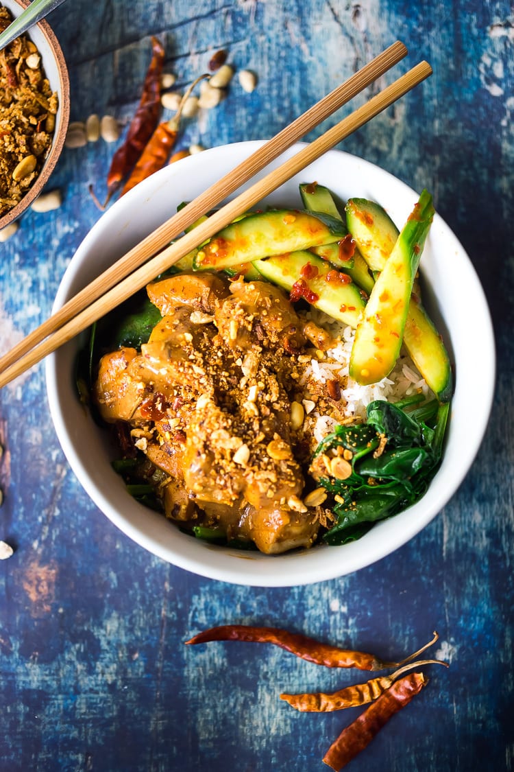 Peanut chicken in a bowl with cucumber salad and rice. 