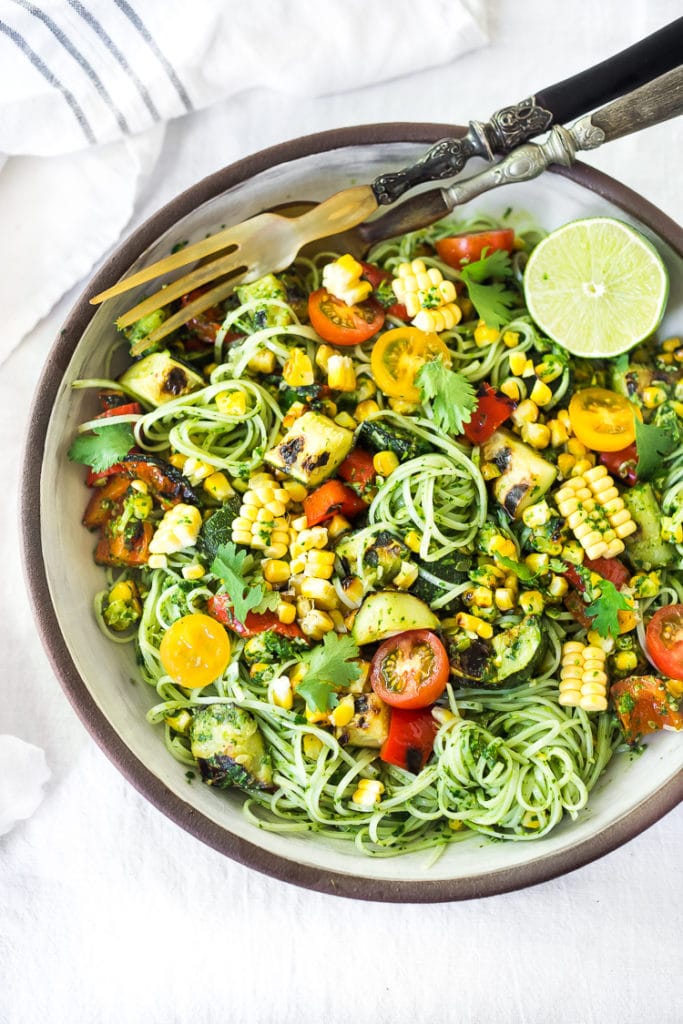 summer pasta salad with noodles, pesto, charred zucchini and corn, and fresh cherry tomatoes.