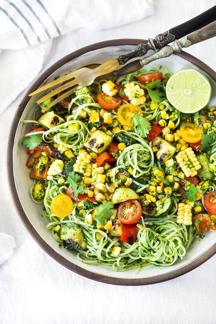 Summer pasta salad in a bowl with corn, zucchini, tomatoes and cilantro pesto.