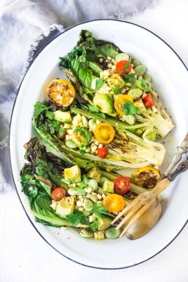 Healthy delicious, Grilled Romaine Salad with Corn, Fava Beans and Avocado - a light and refreshing summer meal. Keep it vegan or add grilled shrimp for added protein. Either way, it's sure to be your new favorite salad. Don't have access to fresh Fava beans? No worries, sub edamame! #grilledromaine #salad #romaine #fava #avocado #grilled #vegan