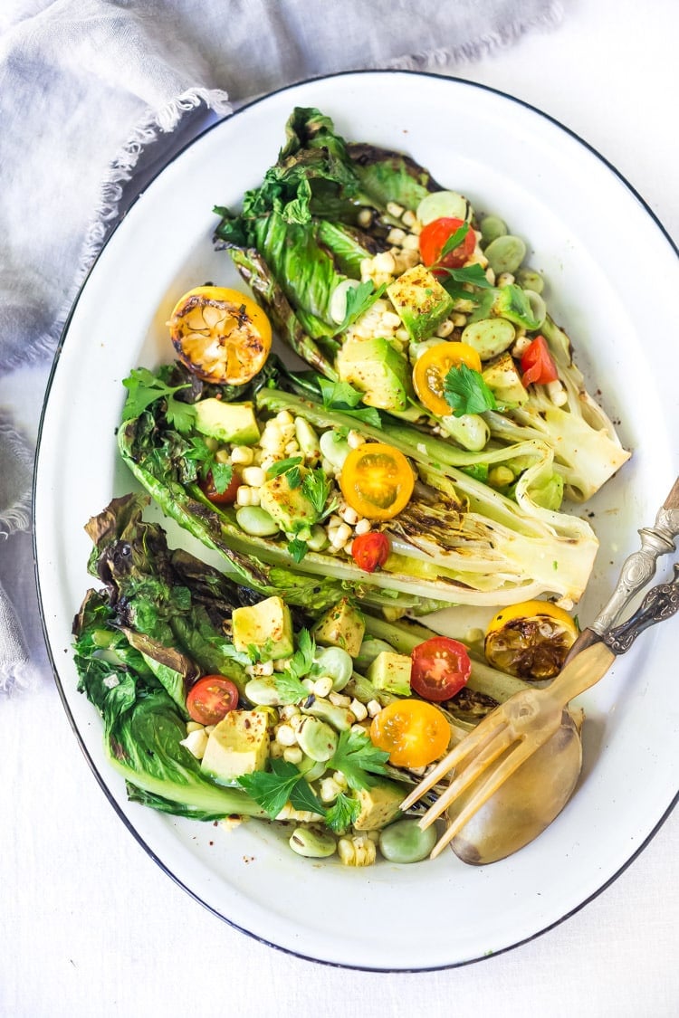 Healthy delicious, Grilled Romaine Salad with Corn, Fava Beans and Avocado - a light and refreshing summer meal. Keep it vegan or add grilled shrimp for added protein. Either way, it's sure to be your new favorite salad. Don't have access to fresh Fava beans? No worries, sub edamame! #grilledromaine #salad #romaine #fava #avocado #grilled #vegan 