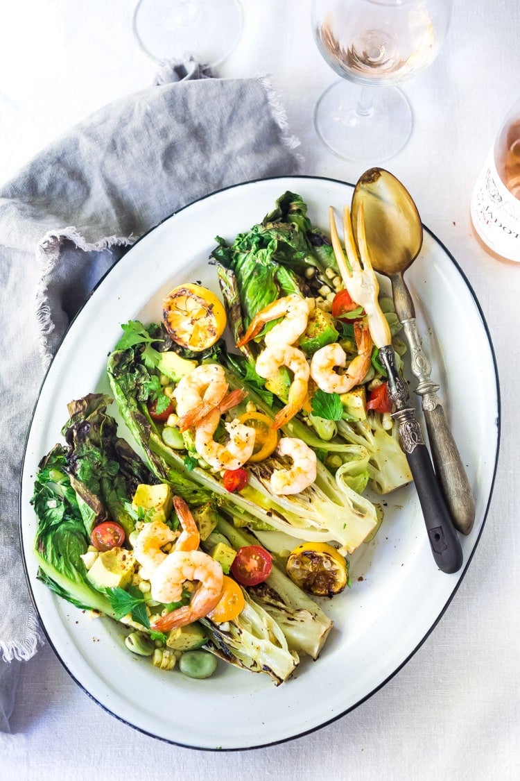 Healthy delicious, Grilled Romaine Salad with Corn, Fava Beans and Avocado - a light and refreshing summer meal. Keep it vegan or add grilled shrimp for added protein. Either way, it's sure to be your new favorite salad. Don't have access to fresh Fava beans? No worries, sub edamame! #grilledromaine #salad #romaine #fava #avocado #grilled #vegan 