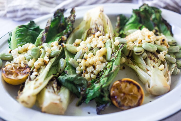 Healthy delicious, Grilled Romaine Salad with Corn, Fava Beans and Avocado - a light and refreshing summer meal. Keep it vegan or add grilled shrimp for added protein. Either way, it's sure to be your new favorite salad. Don't have access to fresh Fava beans? No worries, sub edamame! #grilledromaine #salad #romaine #fava #avocado #grilled #vegan 