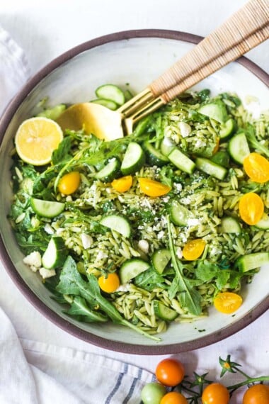 This Orzo Salad is tossed with a lemon basil dressing, with fresh cucumbers, tomatoes and arugula. A healthy, vegan, pasta salad that can be made ahead for midweek lunches or potlucks. Keep it vegan or add feta! 