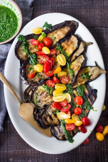 Grilled Eggplant Steaks with Fresh Tomato Relish and an Italian herb sauce called Gremolata. Keep it vegan or add crumbled cheese. A simple, healthy dinner recipe! #eggplant Feastingathome #grilledeggplant #gremolata #eggplantsteaks #eggplantrecipes #eggplantsteaks #healthydinner #meatlessdinner #vegan