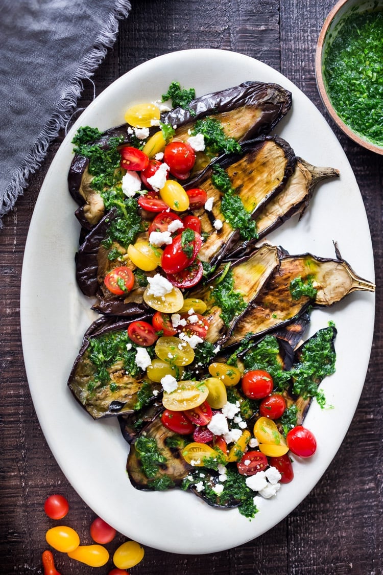 Grilled Eggplant Steaks with Fresh Tomato Relish and an Italian herb sauce called Gremolata. Keep it vegan or add crumbled cheese. A simple, healthy dinner recipe! #eggplant Feastingathome #grilledeggplant #gremolata #eggplantsteaks #eggplantrecipes #eggplantsteaks #healthydinner #meatlessdinner #vegan 