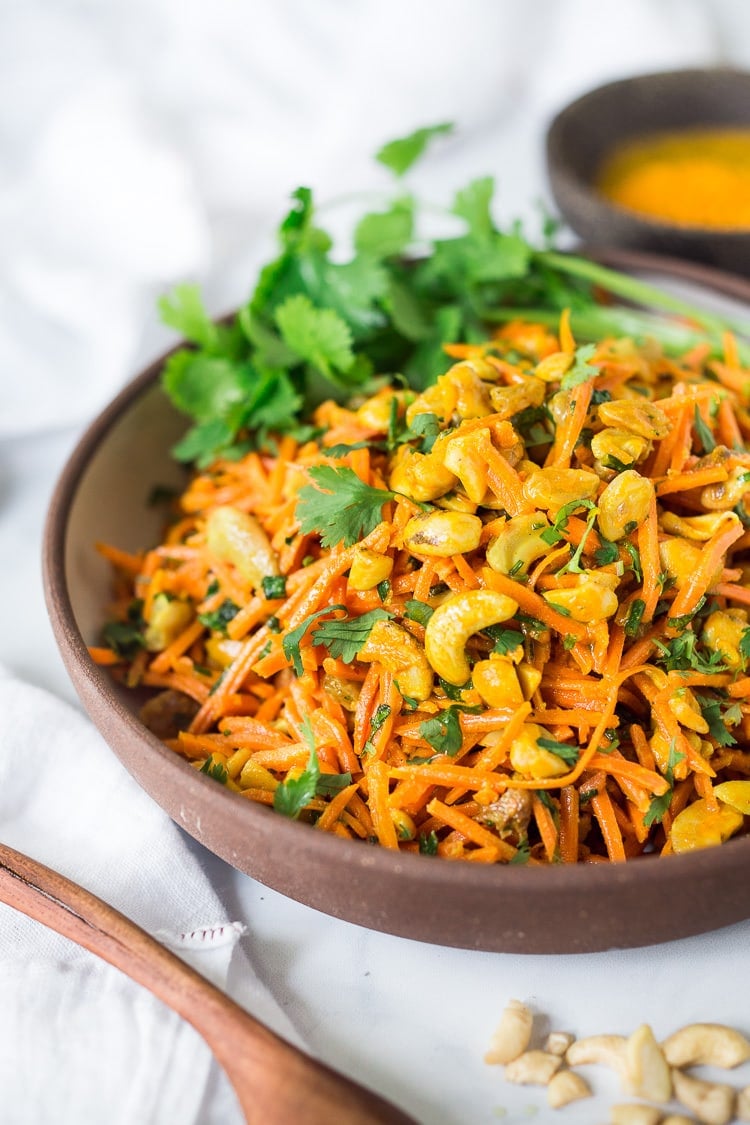 Bombay Carrot Salad with cashews and raisins, tossed in a fragrant Indian Curry dressing. Healthy and vegan this carrot salad recipe is so EASY to make, and can be made-ahead. #carrotsalad #carrotslaw #vegan #indiancarrotsalad #recipe #carrotsaladrecipe 