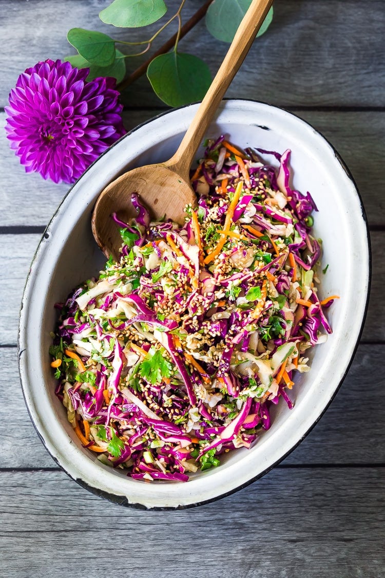 Easy Crunchy Asian Slaw- a simple vegan slaw with the BEST SLAW DRESSING EVER that can be made ahead! Serve this alongside fish, tofu, or chicken or stuffed into tacos, topped onto burgers, or added to buddha bowls. A great way to add more veggies into your everyday meals. #slaw #asianslaw #veganslaw #easyslaw #tacoslaw