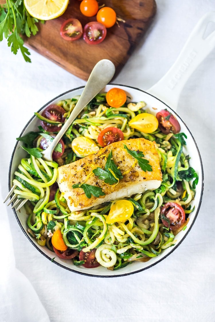 A simple, healthy Halibut recipe served over Lemony Zucchini Noodles with olive oil, garlic and parsley, topped with sweet summer tomatoes. A quick and easy low-carb meal! #keto #zucchininoodles #zoodles #halibut #halibutrecipes #lowcarb #healthy 