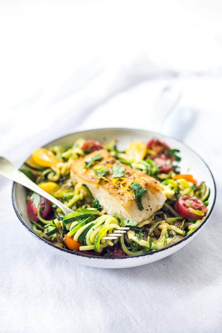 A simple, healthy Halibut recipe served over Lemony Zucchini Noodles with olive oil, garlic and parsley, topped with sweet summer tomatoes. A quick and easy low-carb meal! #keto #zucchininoodles #zoodles #halibut #halibutrecipes #lowcarb #healthy 