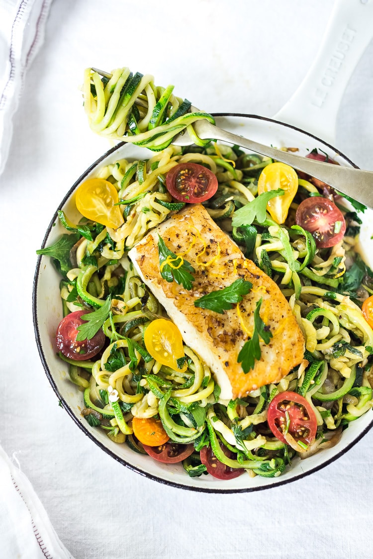 A simple, healthy Halibut recipe served over Lemony Zucchini Noodles with olive oil, garlic and parsley, topped with sweet summer tomatoes. A quick and easy low-carb meal! #keto #zucchininoodles #zoodles #halibut #halibutrecipes #lowcarb #healthy 