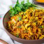 Bombay Carrot Salad with cashews and raisins, tossed in a fragrant Indian Curry dressing. Healthy and vegan this carrot salad recipe is so EASY to make, and can be made-ahead. #carrotsalad #carrotslaw #vegan #indiancarrotsalad #recipe #carrotsaladrecipe