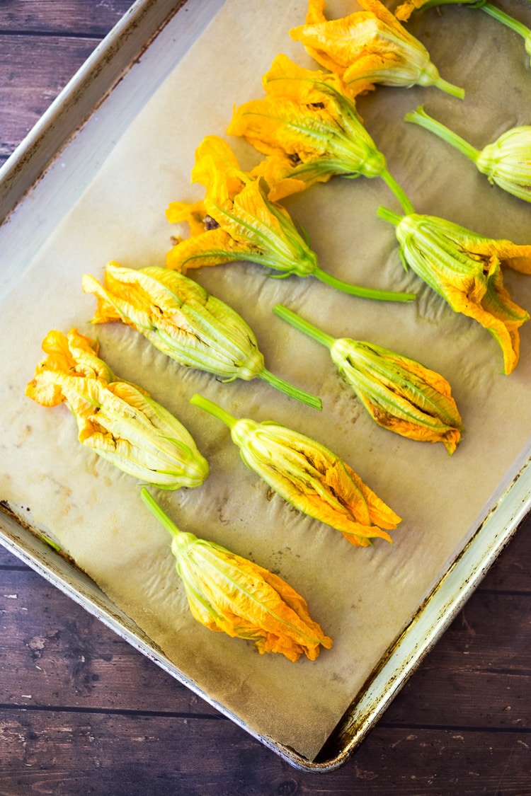 Baked Squash Blossoms with ground lamb, basmati rice and fragrant Middle Eastern spices - a simple delicious appetizer, or main course inspired by the season! Serve with Creamy Tzatziki Sauce! #squashblossoms #zuccinniblossoms #dolmas