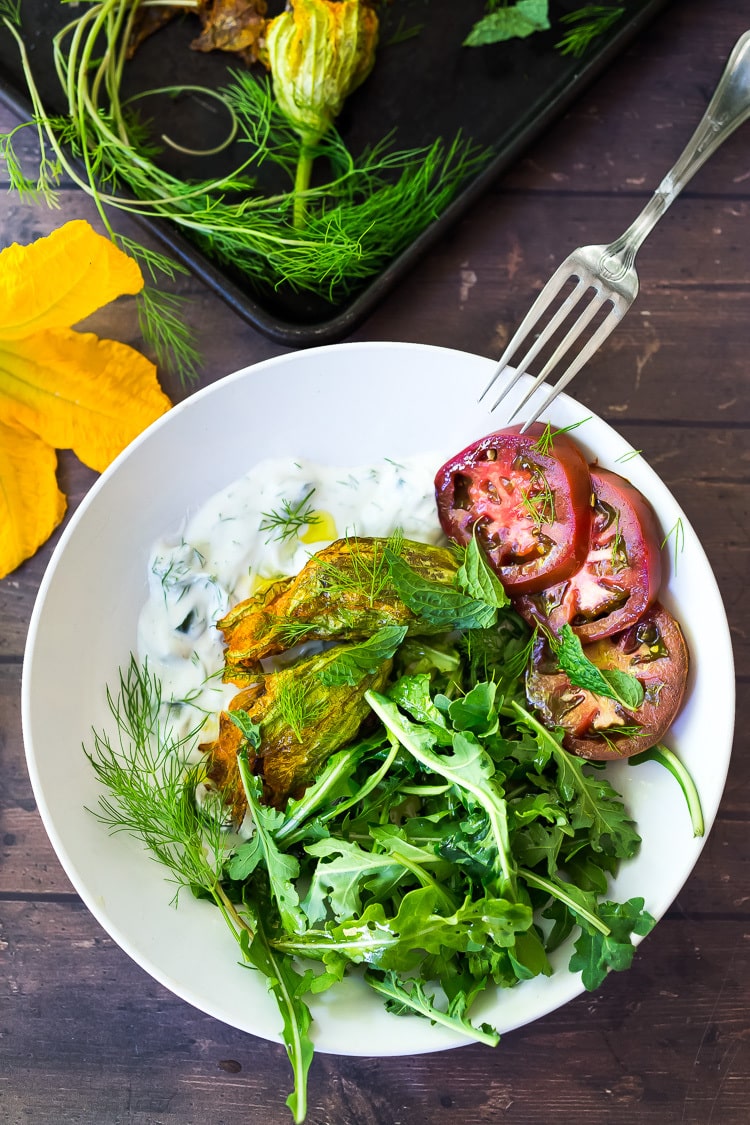 Baked Squash Blossoms with ground lamb, basmati rice and fragrant Middle Eastern spices - a simple delicious appetizer, or main course inspired by the season! Serve with Creamy Tzatziki Sauce! #squashblossoms #zuccinniblossoms #dolmas