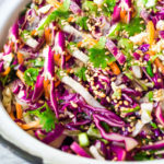 Easy Crunchy Asian Slaw- a simple vegan slaw with the BEST SLAW DRESSING EVER that can be made ahead! Serve this alongside fish, tofu, or chicken or stuffed into tacos, topped onto burgers, or added to buddha bowls. A great way to add more veggies into your everyday meals. #slaw #asianslaw #veganslaw #easyslaw #tacoslaw