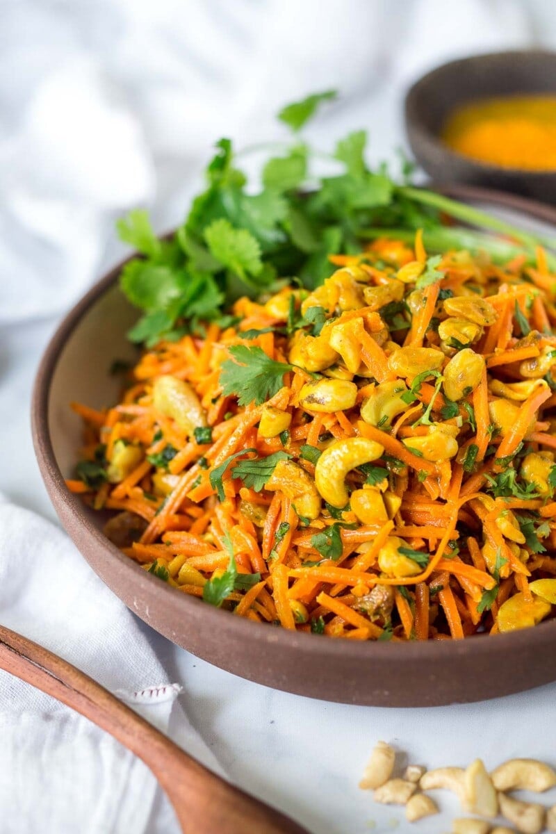 This Carrot Raisin Salad is studded with cashews and tossed in the most flavorful Indian curry dressing.  Simple to make, healthy vegan, this carrot salad recipe is so addicting! 