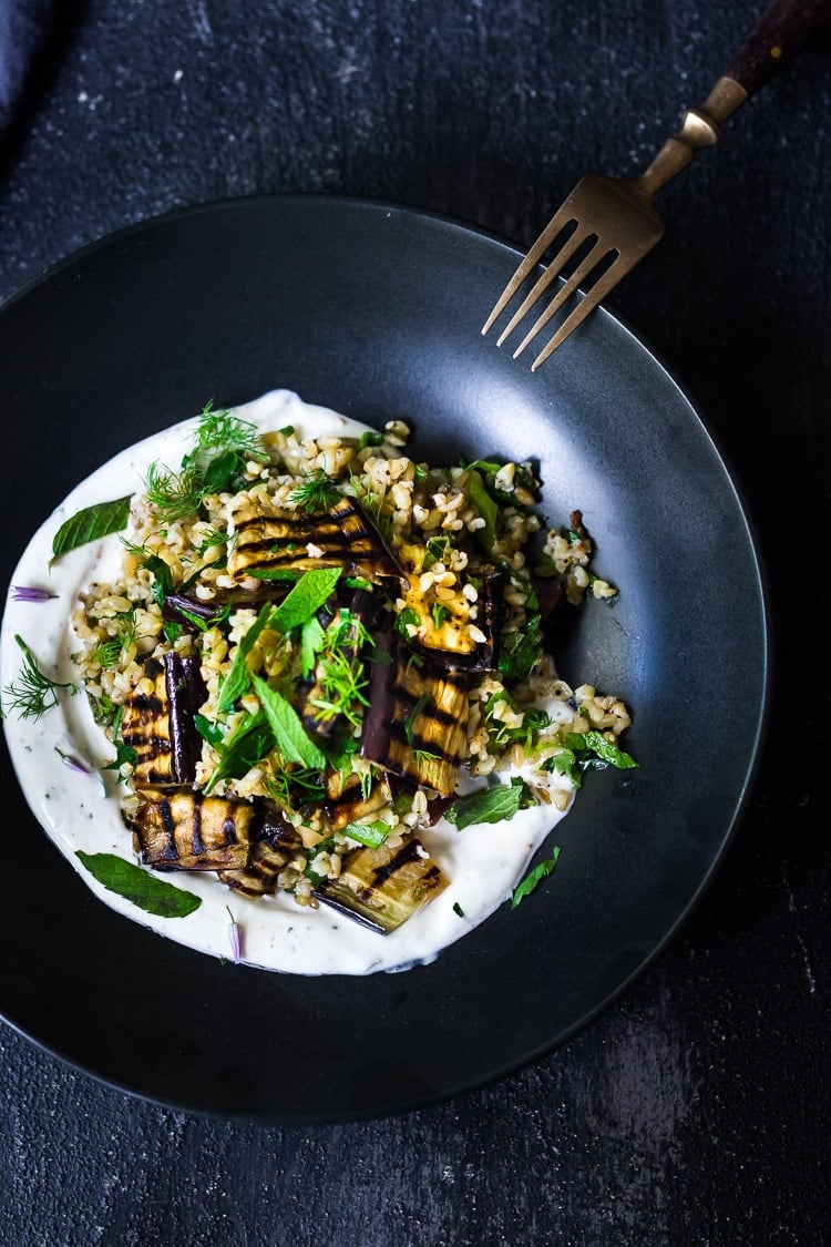 Grilled Eggplant Salad with Freekah. Loaded up with fresh herbs and served over a tangy yogurt dressing, this healthy salad is full of Middle Eastern flavor. Vegan adaptable #freekah #eggplantsalad #freekahsalad #freekahrecipe #vegetarian #vegan #healthysalad