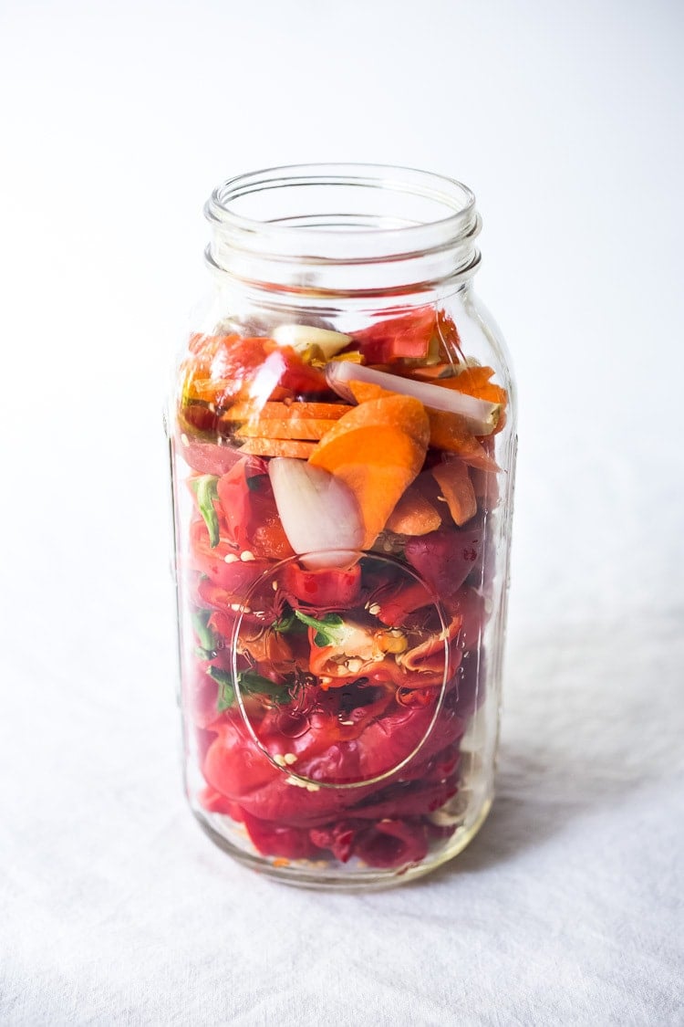 layering the veggies and chilies in the mason jar.