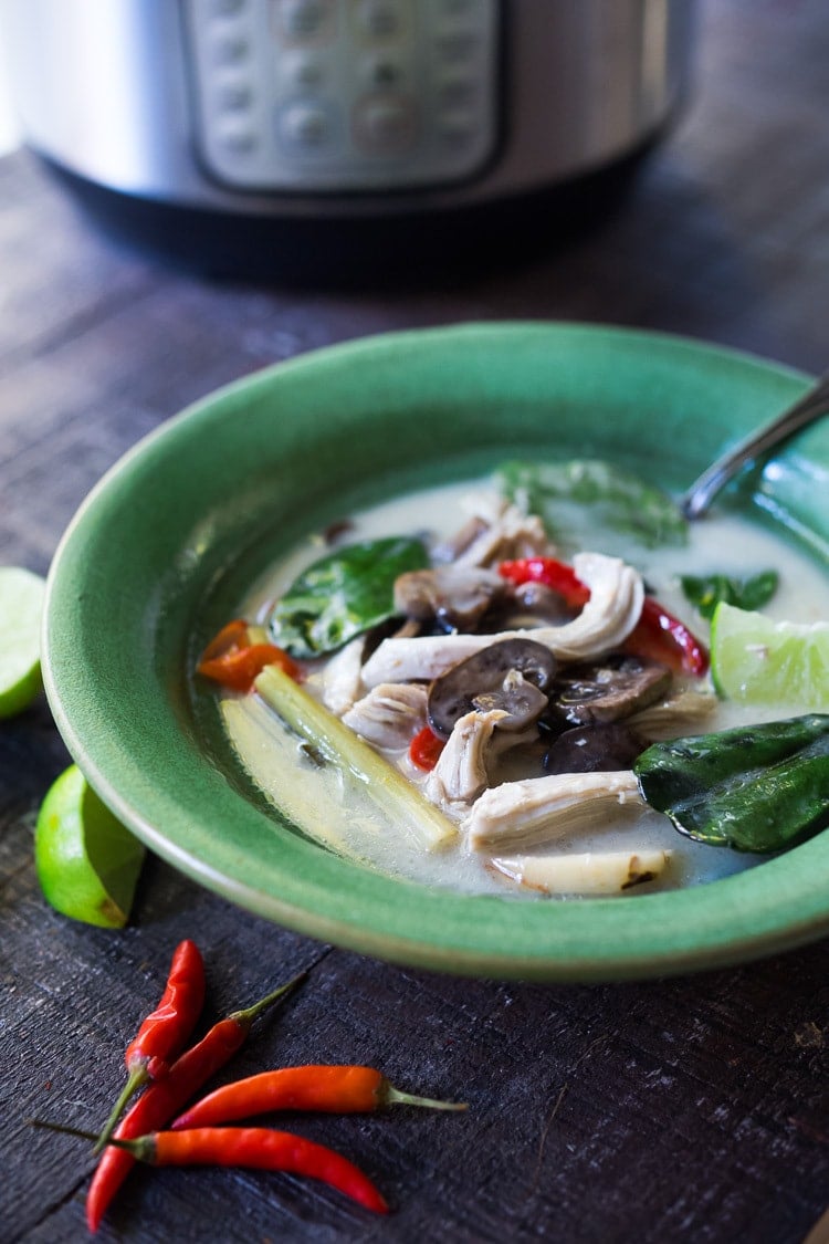 Authentic Tom Kha Gai Soup (Thai Coconut Chicken Soup) in bowl with chicken, mushrooms, kaffir lime leaves, lemongrass, chilies, in front on Instant Pot.