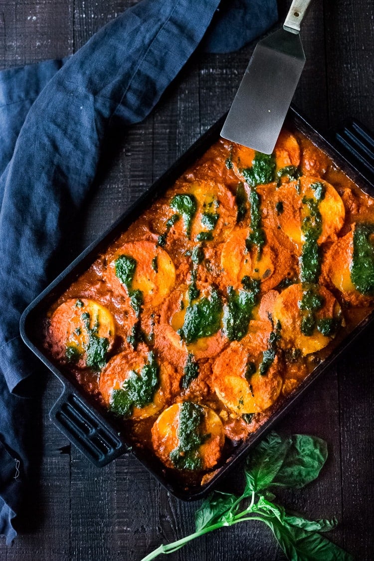 A pan of baked polenta lasagna with pesto drizzle. 