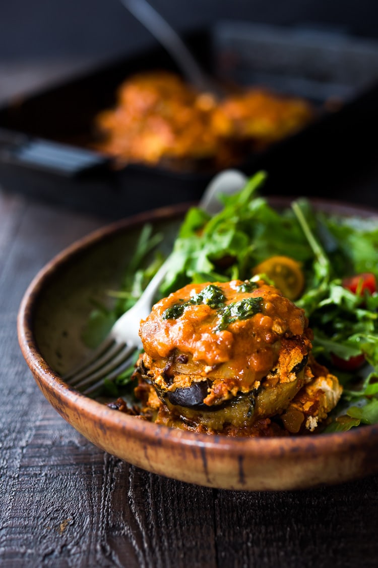 A serving of polenta lasagna with a leafy green salad in a bowl. 