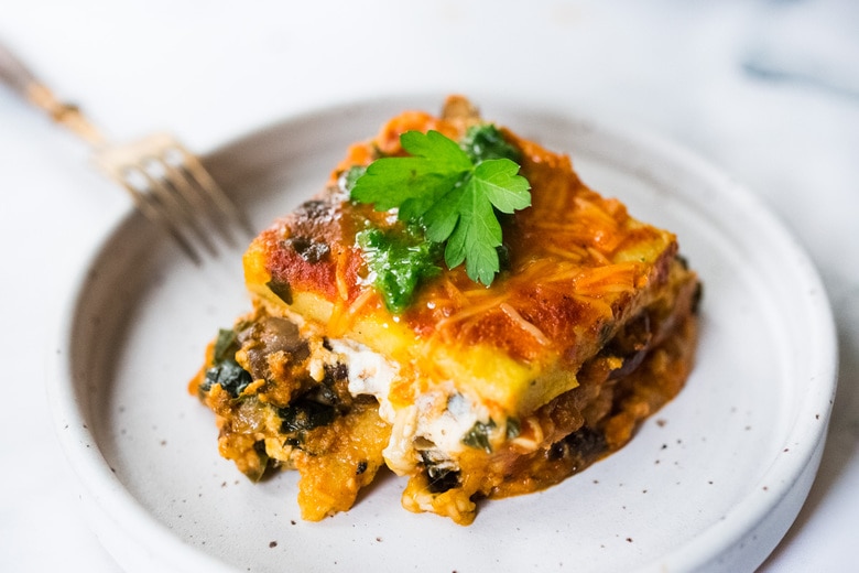 Polenta Lasagna with Roasted Red Pepper Sauce - an easy, vegan adaptable main dish that is perfect for the holiday table. Gluten-free! #veganthanksgiving #polentalasagna #veganlasagna #vegetarianmaindish #veganchristmas #polenta #lasagnarecipes #glutenfreelasagna 