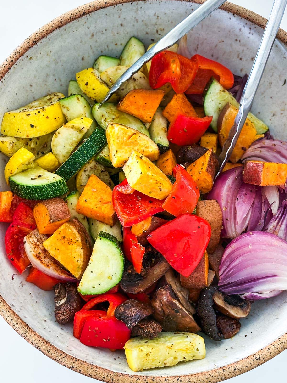 Tossing the vegetables in a bowl with olive oil and seasonings.