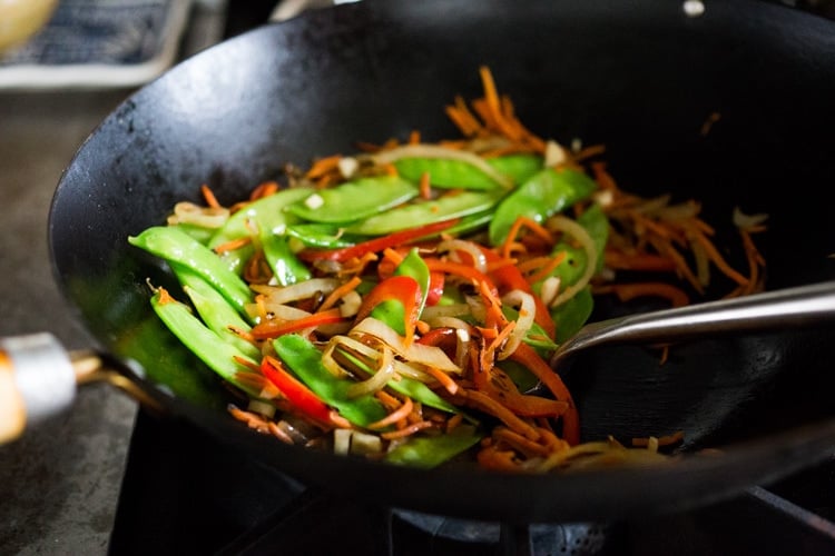 Stirfrying vegetables for Singapore noodles in a wok.