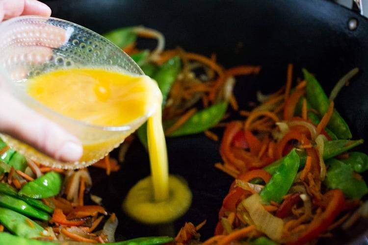 Adding egg to the wok for Singapore noodles.