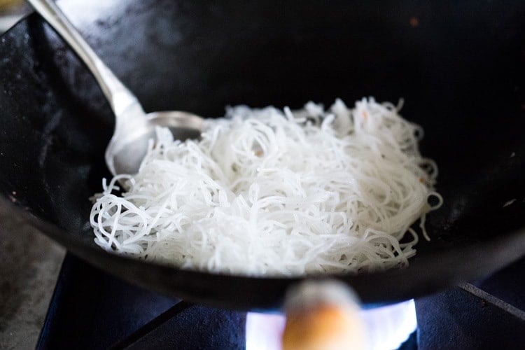 Stirfrying noodles for Singapore noodles in a wok.