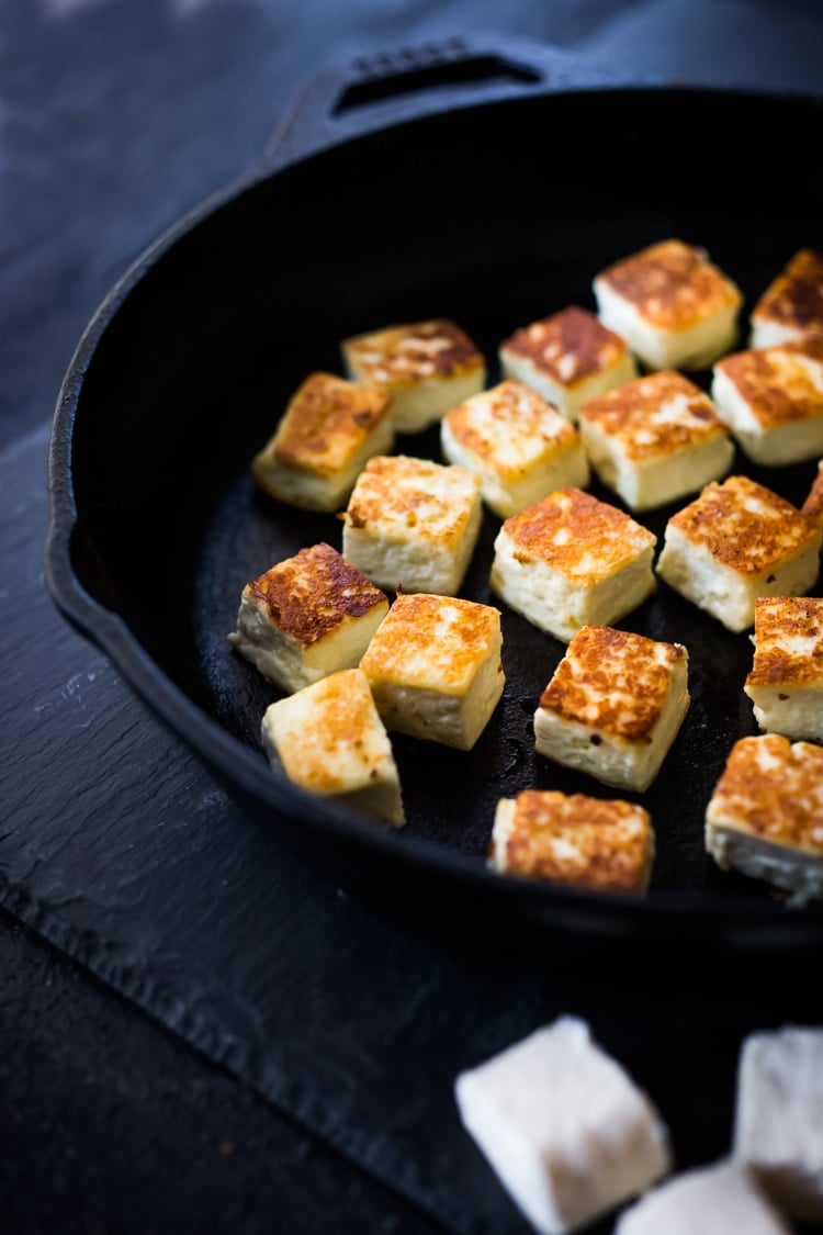 Crispy cubes of paneer, golden brown, in a skillet