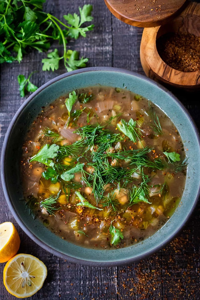soup bowl with lemony chickpea soup garnished with fresh parsley and dill.
