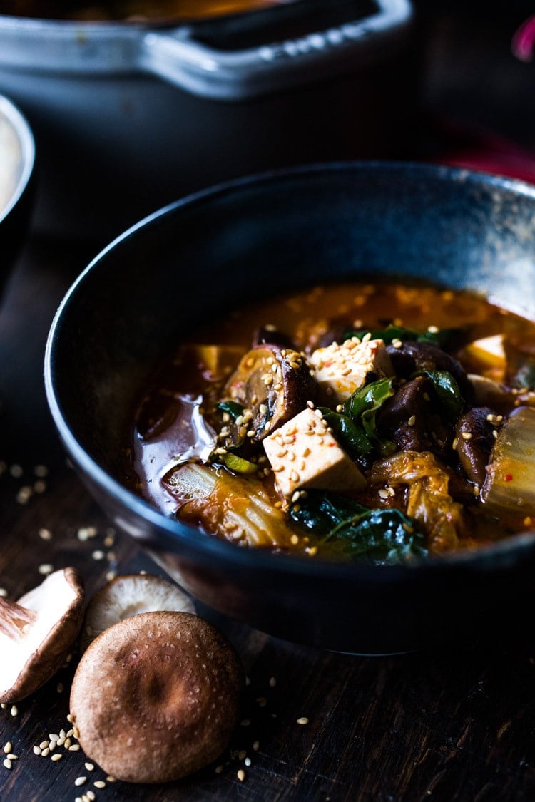 A simple easy recipe for Kimchi Soup- this version is vegan, made with shiitake mushrooms, silken tofu and kale. Serve over rice or noodles! Delicious Korean flavor! #kimchisoup #easykimchisoup #vegankimchisoup #plantbased #cleaneating #eatclean #vegansoup #koreansoup