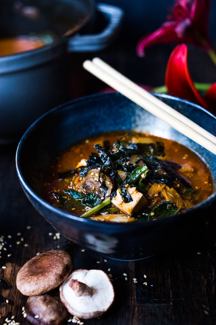 A simple easy recipe for Kimchi Soup- this version is vegan, made with shiitake mushrooms, silken tofu and kale. Serve over rice or noodles! Delicious Korean flavor! #kimchisoup #easykimchisoup #vegankimchisoup #plantbased #cleaneating #eatclean #vegansoup #koreansoup 