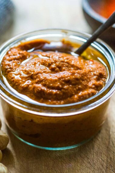romesco sauce in a bowl with chili flakes and fresh herbs.