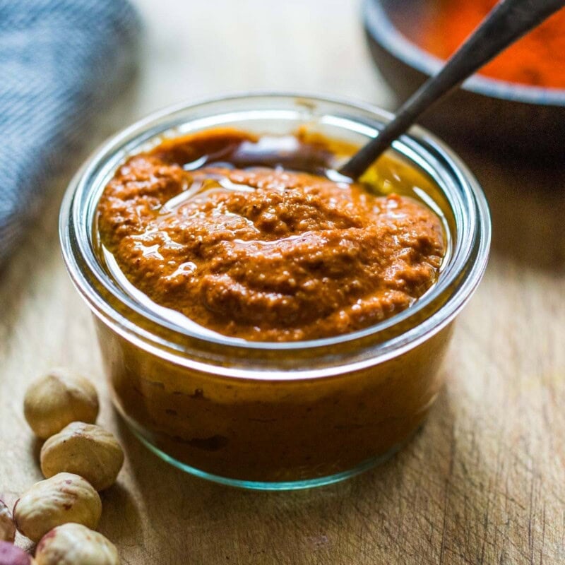 romesco sauce in a bowl with chili flakes and fresh herbs.