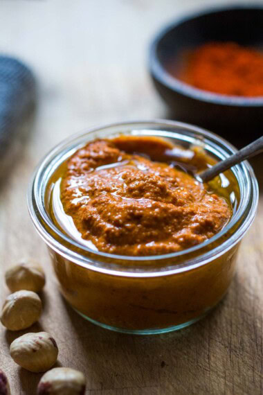 romesco sauce in a bowl with chili flakes and fresh herbs.