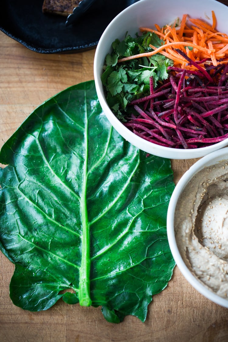 Rainbow Wraps! This vegan collard greens wraps are filled with hummus, crispy tofu, shredded beets, carrots and avocado! Drizzle with Tahini sauce! A delicious healthy lunch! #eatclean #cleaneating #vegan #veganlunch #rainbowwrap #Wraps #veganwrap #plantbased #collardgreens