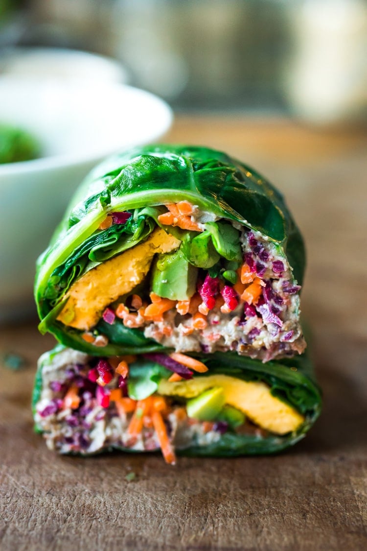Rainbow Wraps! This vegan collard greens wraps are filled with hummus, crispy tofu, shredded beets, carrots and avocado! Drizzle with Tahini sauce! A delicious healthy lunch! #eatclean #cleaneating #vegan #veganlunch #rainbowwrap #Wraps #veganwrap #plantbased #collardgreens