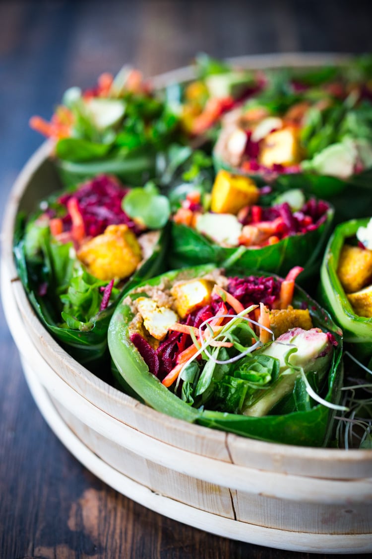 Rainbow Wraps! This vegan collard greens wraps are filled with hummus, crispy tofu, shredded beets, carrots and avocado! Drizzle with Tahini sauce! A delicious healthy lunch! #eatclean #cleaneating #vegan #veganlunch #rainbowwrap #Wraps #veganwrap #plantbased #collardgreens