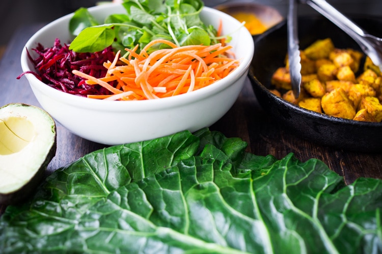 Rainbow Wraps! This vegan collard greens wraps are filled with hummus, crispy tofu, shredded beets, carrots and avocado! Drizzle with Tahini sauce! A delicious healthy lunch! #eatclean #cleaneating #vegan #veganlunch #rainbowwrap #Wraps #veganwrap #plantbased #collardgreens