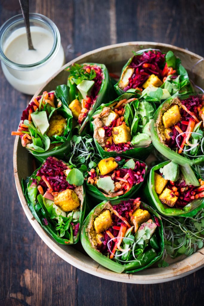 Collard greens wraps are filled with hummus, crispy tofu, shredded beets, carrots and avocado! Drizzle with Tahini sauce! A delicious healthy lunch! #eatclean #cleaneating #vegan #veganlunch #rainbowwrap #Wraps #veganwrap #plantbased #collardgreens