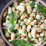 Corona Beans- giant buttery white beans seasoned with olive oil, garlic, fresh herbs and lemon zest. Serve as a vegan main or side dish or add to salads and Buddha Bowls. #corona #beans #whitebeans #Gigantes #royalcoronabeans