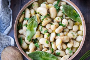 Corona Beans- giant buttery white beans seasoned with olive oil, garlic, fresh herbs and lemon zest. Serve as a vegan main or side dish or add to salads and Buddha Bowls. #corona #beans #whitebeans #Gigantes #royalcoronabeans