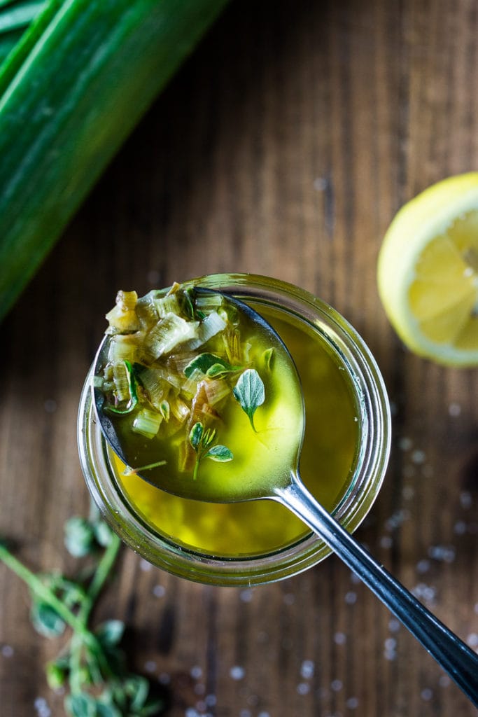glass jar of lemony leek dressing with a spoon resting on top.