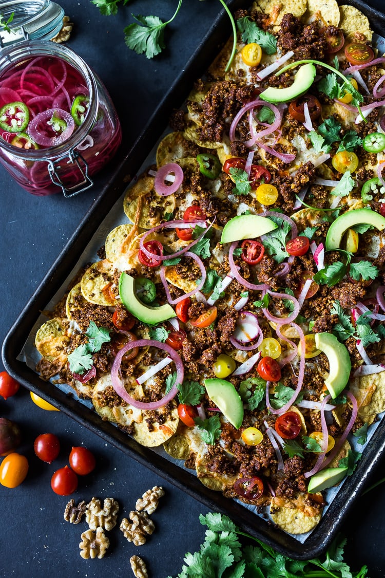 This vegan nacho recipe is loaded up with healthy veggies and made with flavorful vegan chorizo and optional vegan queso.  A wholesome, no-guilt nacho recipe that is delicious, and easy, baked in the oven. Vegan and Gluten-free!