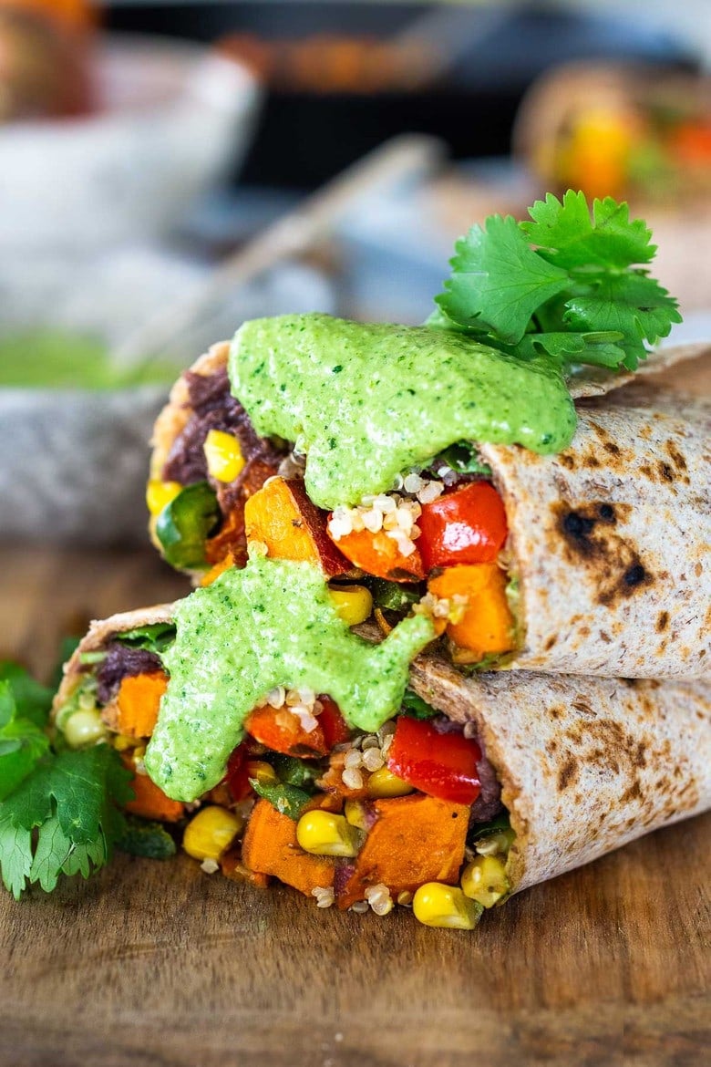 These Vegan Peruvian Burritos are filled with roasted sweet potato, fresh corn, peppers, quinoa and creamy blackbeans, then drizzled with spicy Peruvian Green Sauce. A flavor bomb! Vegan and Delicious! #vegan #burrito #peruvianfood #peruvianrecipes #veganburrito 
