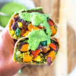 These Vegan Peruvian Burritos are filled with roasted sweet potato, fresh corn, peppers, quinoa and creamy blackbeans, then drizzled with spicy Peruvian Green Sauce. A flavor bomb! Vegan and Delicious! #vegan #burrito #peruvianfood #peruvianrecipes #veganburrito