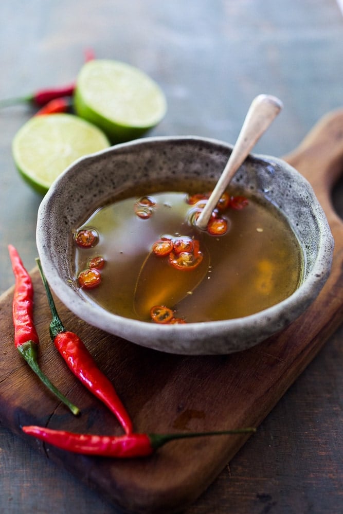 nuoc cham in small bowl with spoon and sliced red chilies.