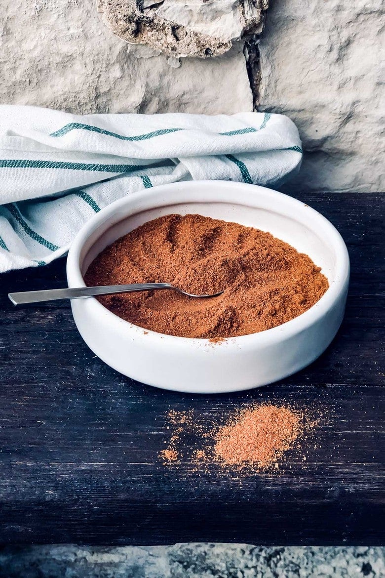 homemade ras el hanout spice blend in small bowl with spoon.